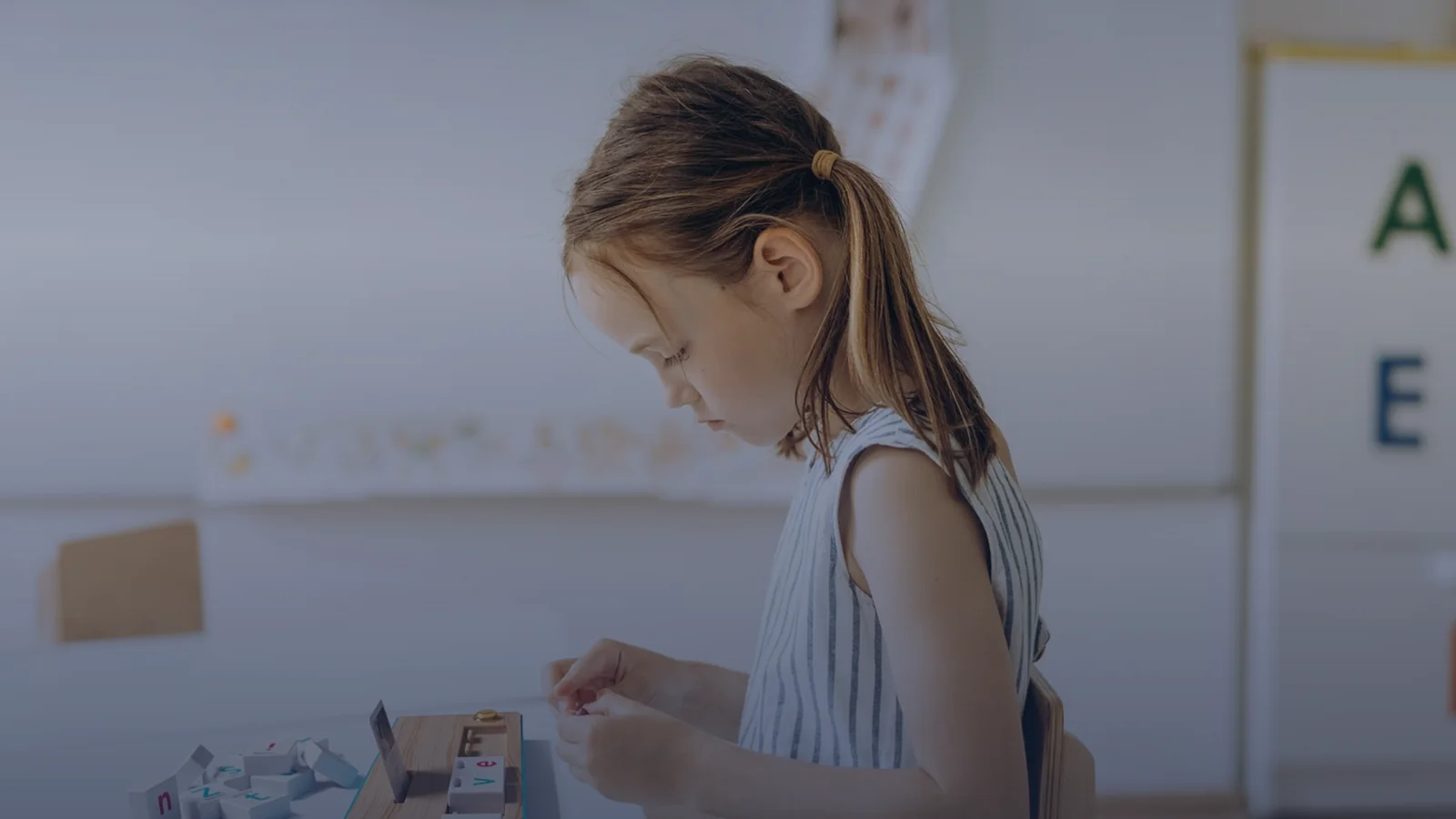 Une enfant compose un mot avec les pavés-lettres sur la station Lilémø, en séance